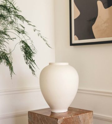 vase blanc sur piédestal en marbre beige avec cadre au mur tendance