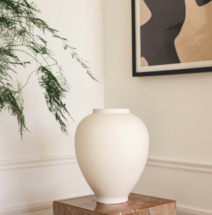 vase blanc sur piédestal en marbre beige avec cadre au mur tendance